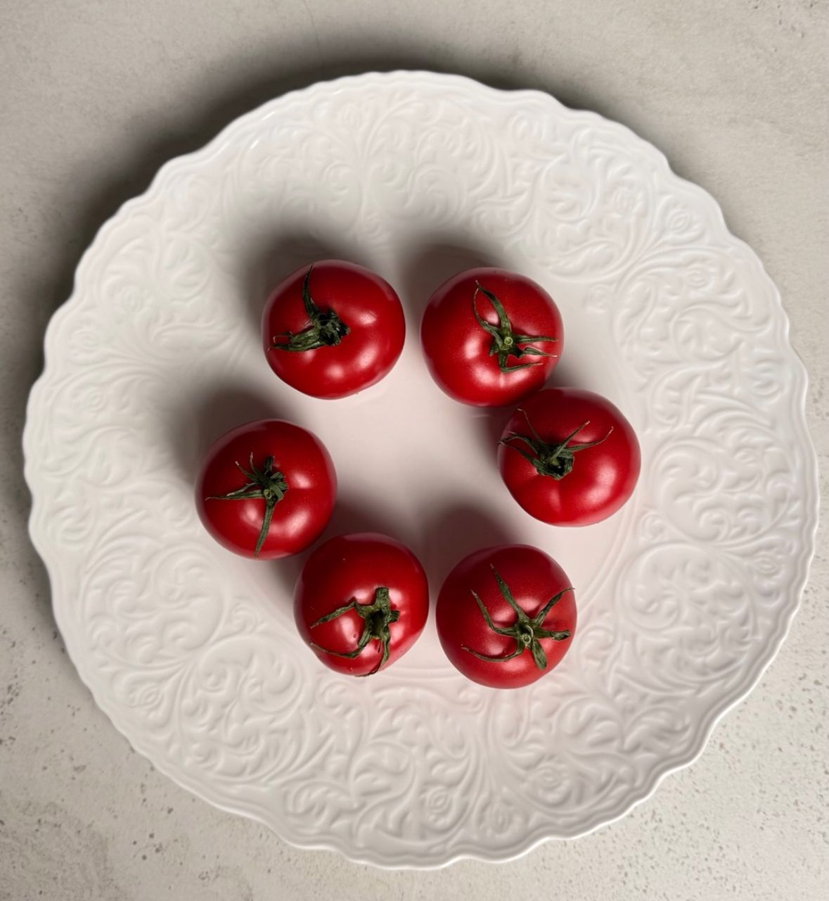 Premium pink tomato sliced on a matte black ceramic plate